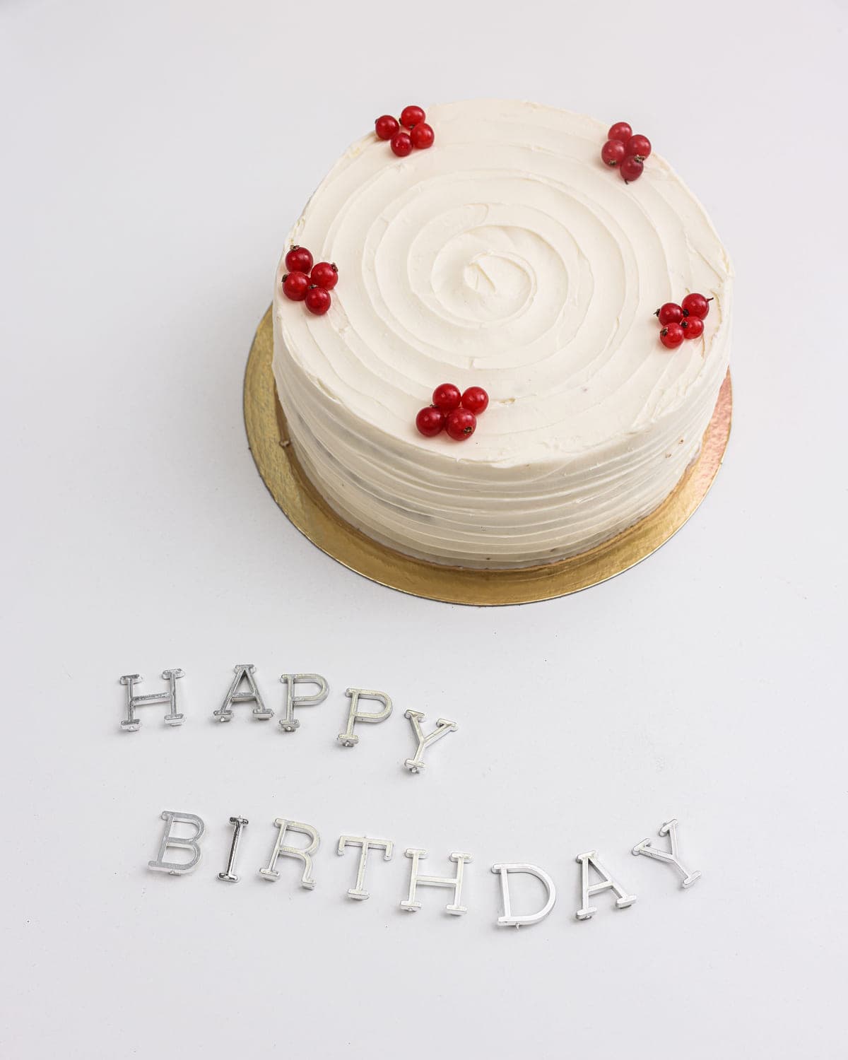 Minimal white frosted cake with delicate piped lettering, seen from above