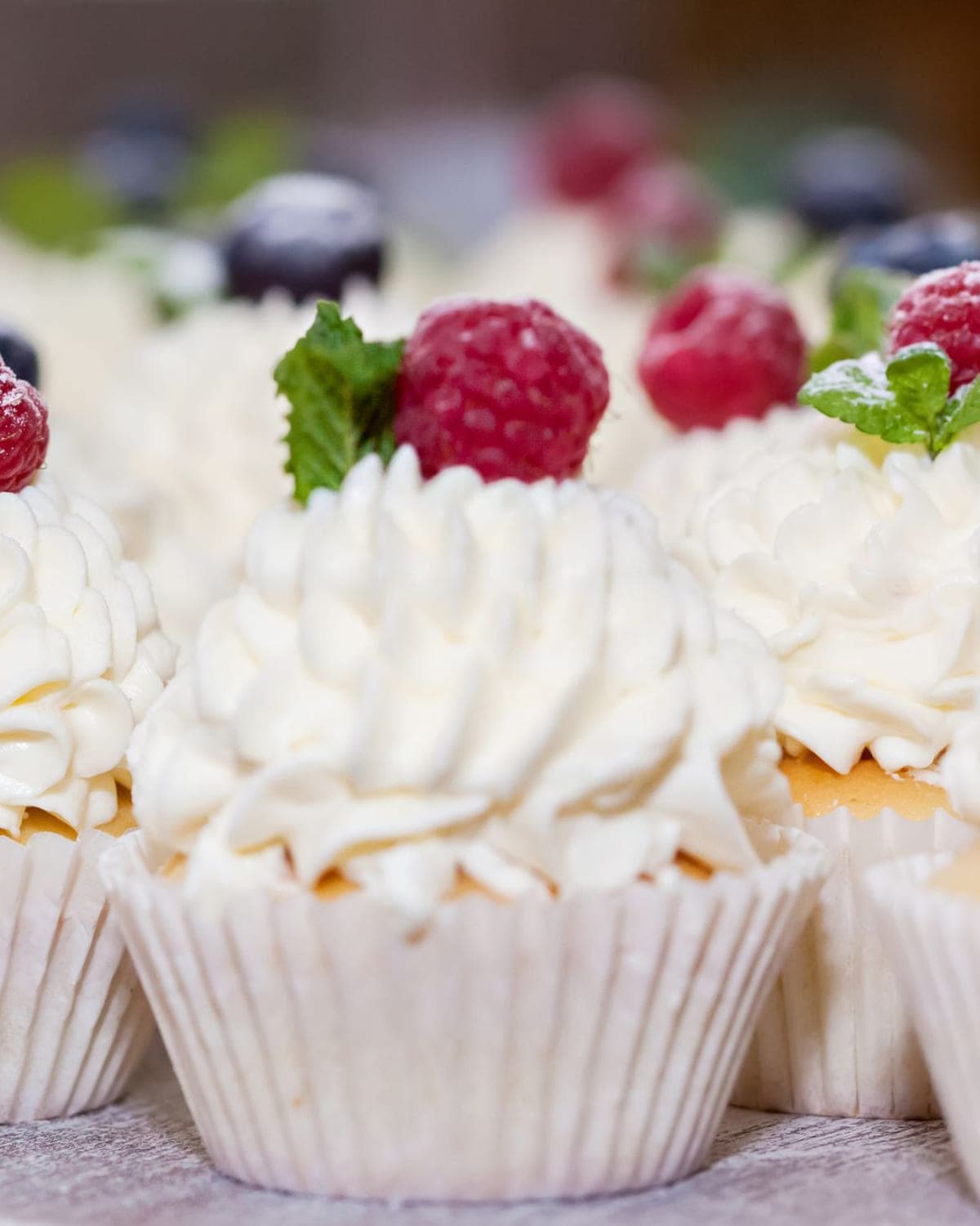 Cupcakes topped with cream swirls and fresh raspberries