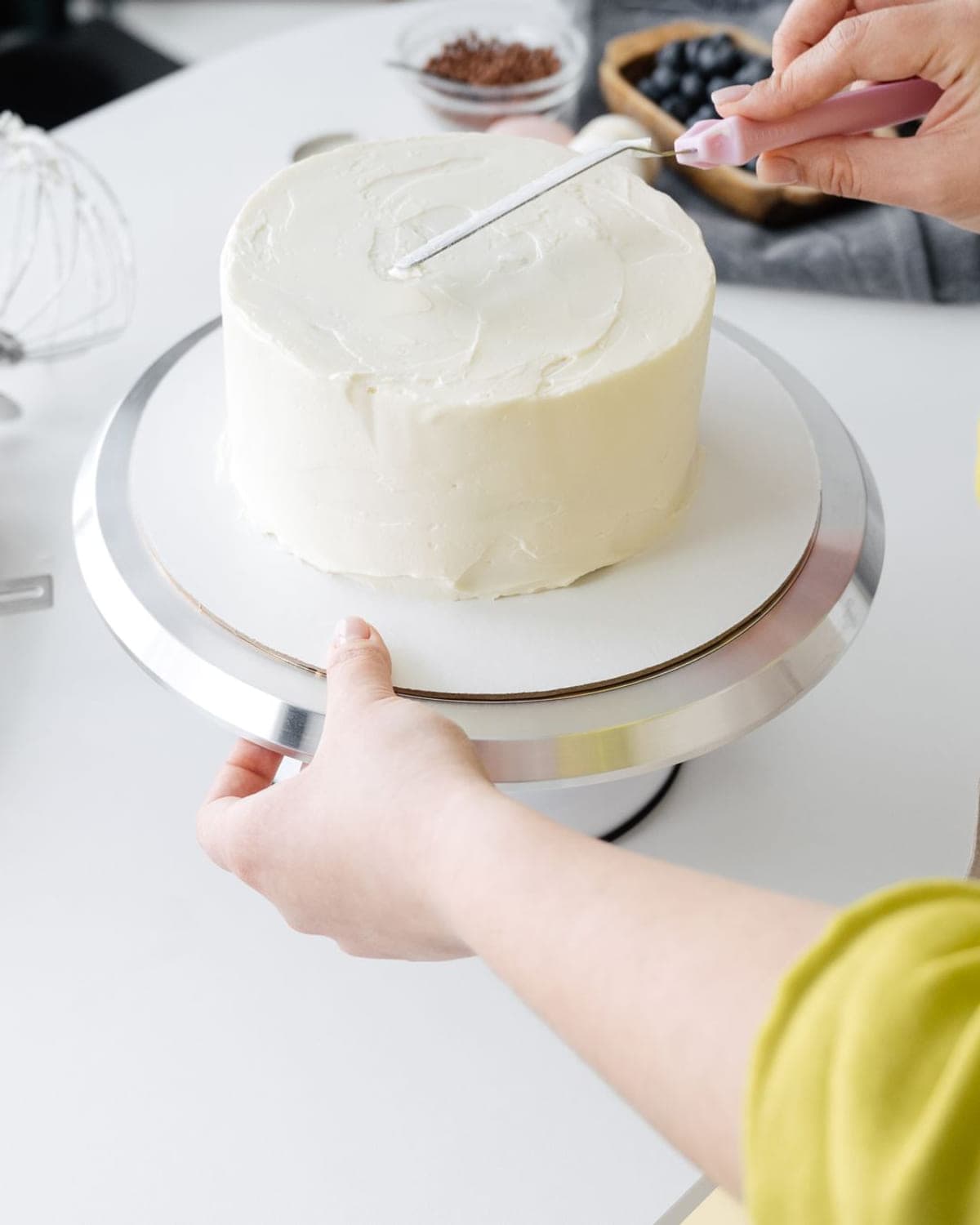 Buttercream being smoothed on a cake turntable