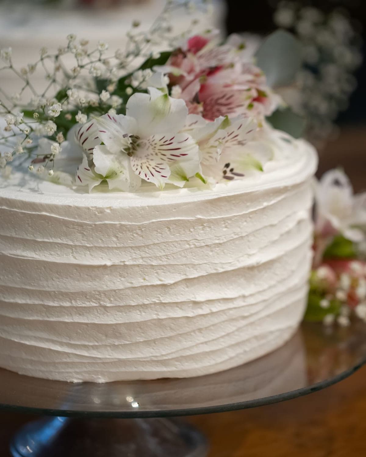 Ivory cake finished with fresh flowers on a glass stand
